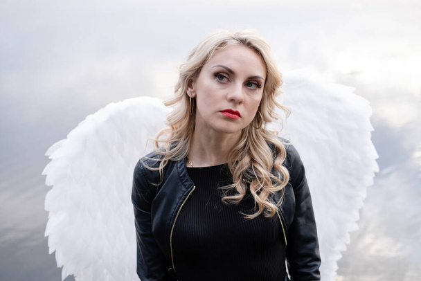 Έκπτωτος άγγελος. κορίτσι σε μαύρο με λευκά φτερά αγγέλου - Φωτογραφία, εικόνα