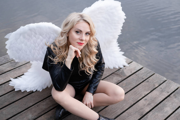 Ángel caído. chica en negro con alas de ángel blanco - Foto, imagen