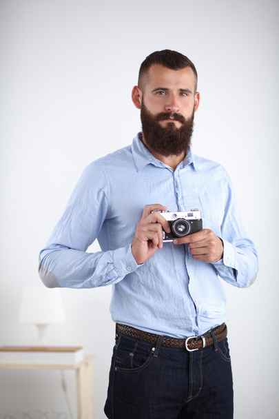 Young beard man focusing at you with his camera while standing against white background - Foto, Bild
