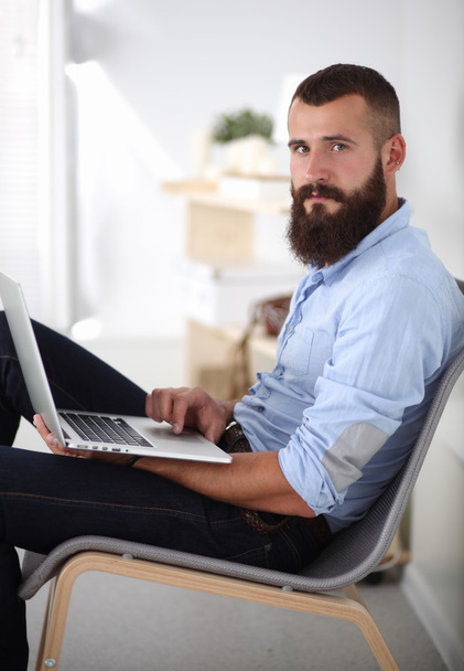 Jóképű fiatalember ül és dolgozik laptop számítógép. - Fotó, kép
