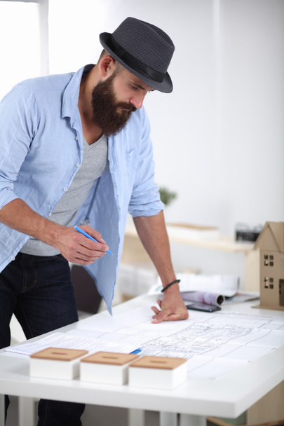 Portrait of male designer in hat with blueprints at desk - Фото, зображення