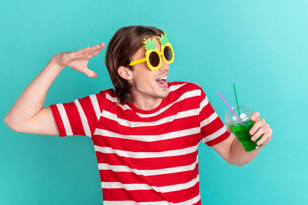 Portrait of attractive cheerful funky guy drinking juice pool party time isolated over bright teal turquoise color background - Fotoğraf, Görsel
