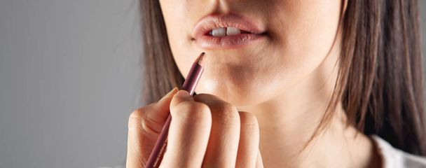 una giovane ragazza si dipinge le labbra con una matita - Foto, immagini