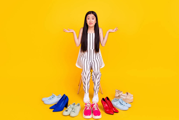 Full length body size photo girl cant choose footwear in shopping mall shrugging shoulders isolated vivid yellow color background - Fotografie, Obrázek