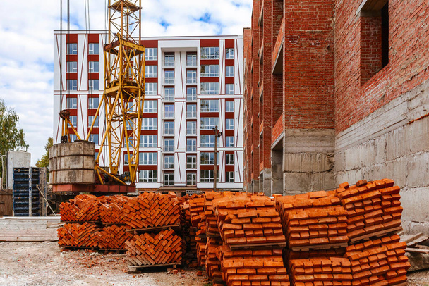 Brick pallets and a tower crane on a construction site near the building - Photo, Image