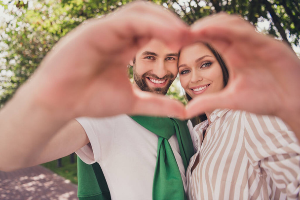 Photo portrait young couple spending time in park sunny weather showing heart sign on date - Photo, image