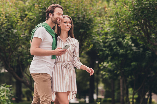 Photo portriat young couple smiling in summer weather in casual clothes man keeping cellphone - Foto, Bild