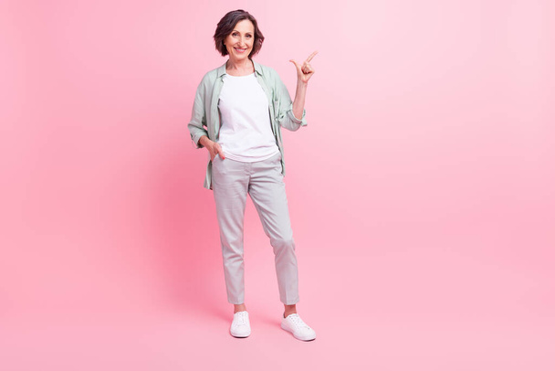 Full length photo of cheerful attractive person indicate finger empty space proposition isolated on pink color background - Zdjęcie, obraz