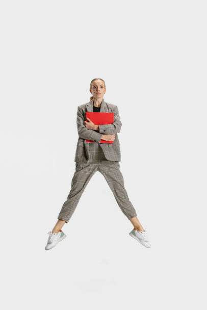 Полнометражный портрет женщины, офисного работника в прыжке с изолированной папкой на белом фоне. - Фото, изображение
