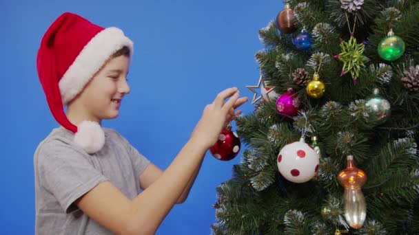 gelukkig kleine jongen versieren kerstboom met ballen. - Video