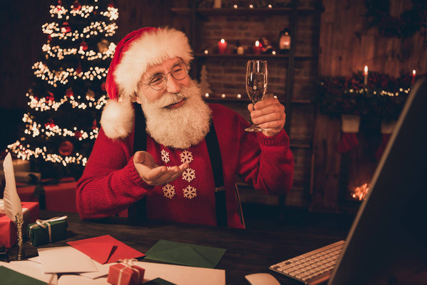 Photo portrait cheerful smiling santa drinking champagne talking on webcam wearing glasses headwear sweater - Foto, Bild