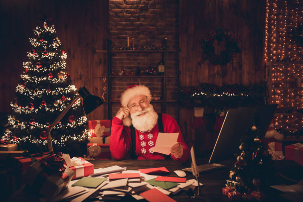 Photo portrait santa claus smiling on xmas sitting at table reading letters with wishes wearing glasses - Foto, Imagem