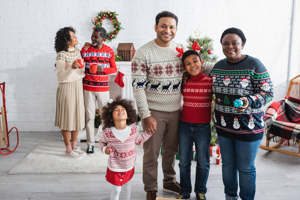 щасливі афроамериканські діти біля батька і бабусі у вітальні з різдвяним прикрасою
 - Фото, зображення