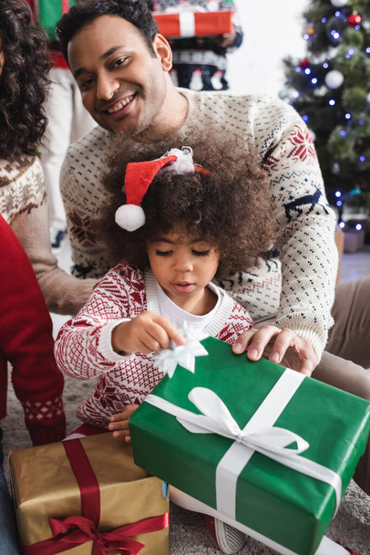 african american girl in santa hat near christmas presents and happy parents - Fotografie, Obrázek