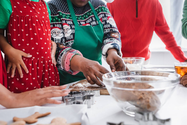 vista recortada de la mujer afroamericana de mediana edad preparando pastelería de Navidad cerca de la familia - Foto, imagen