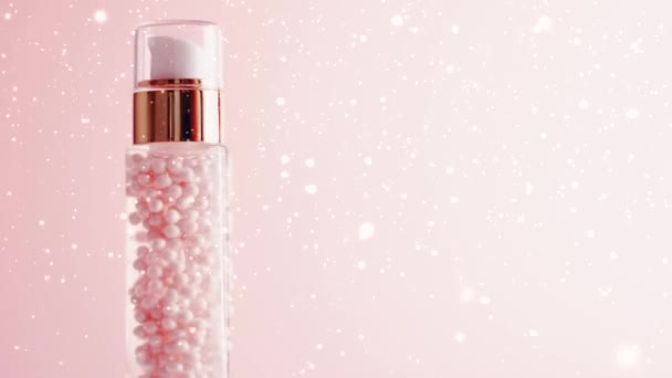 Косметический продукт по уходу за кожей на розовом фоне с зимним снегом и блестками, макияжем и косметикой - Кадры, видео