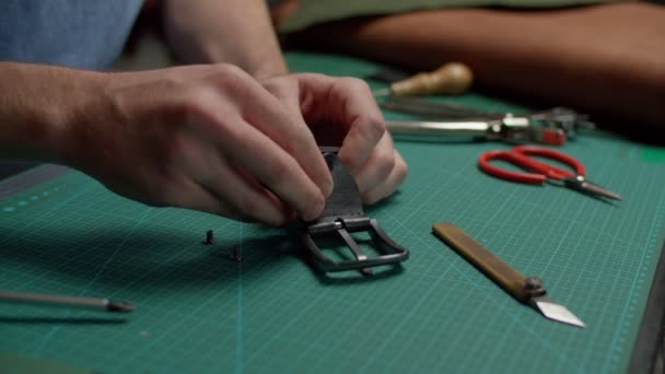 Craftsman getting pieces of disassembled leather belt together indoors - Footage, Video
