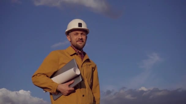 Työnjohtaja rakennustyömaalla kannettavan tietokoneen ja kypärän kanssa - Materiaali, video