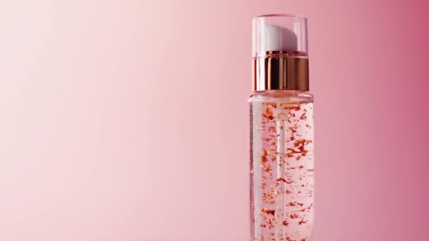 Żel do pielęgnacji skóry w złotej butelce na różowym tle - Materiał filmowy, wideo
