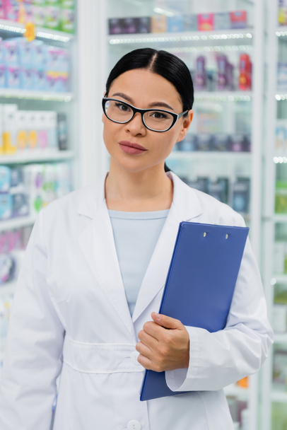 asiatico farmacista in occhiali e mentre cappotto tenendo appunti - Foto, immagini