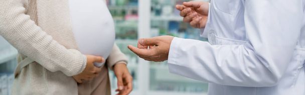 vista ritagliata del farmacista gesticolando vicino alla donna incinta in farmacia, banner - Foto, immagini