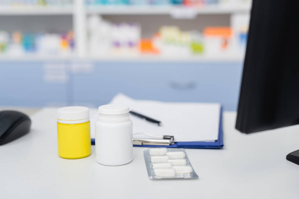 bottles and blister pack with medication near blurred clipboard  - Foto, imagen