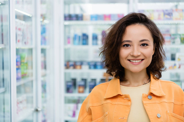 happy and tattooed woman smiling in drugstore - Fotó, kép