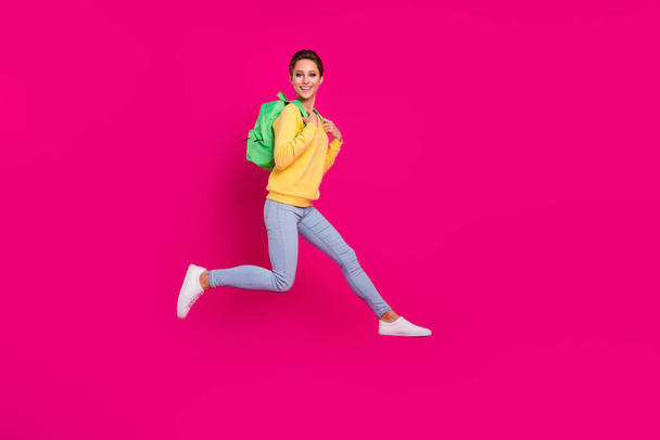 Photo of adorable sweet young woman dressed yellow pullover backpack jumping smiling isolated pink color background - Photo, image