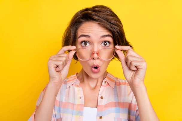 Photo of amazed shocked young woman reaction information wear glasses news isolated on yellow color background - 写真・画像
