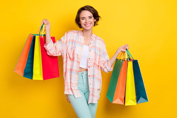 Portrait of attractive cheerful girl holding new things order visit store isolated over shine yellow color background - Foto, imagen