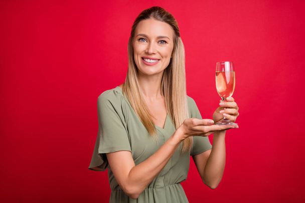 Photo of optimistic mature blond lady index champagne wear khaki dress isolated on red color background - Foto, Imagen