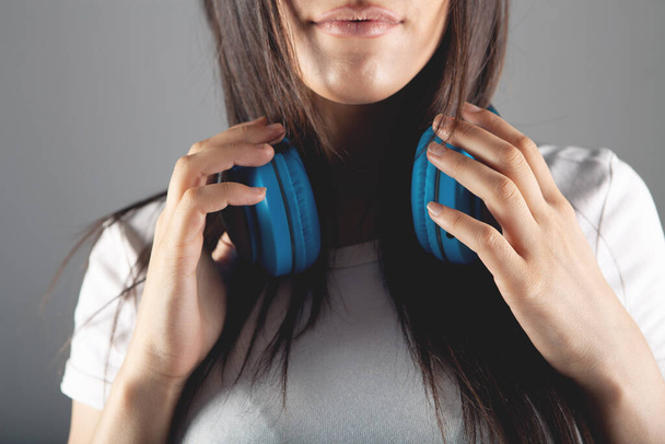 young woman stands in large headphones on a gray background - Photo, image
