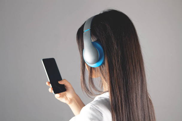 ein junges Mädchen steht mit Kopfhörer und Telefon - Foto, Bild