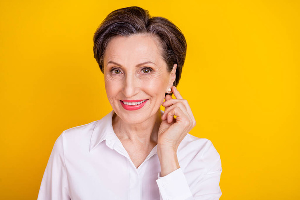 Photo of sweet shiny mature lady wear white clothes arm ear empty space smiling isolated yellow color background - 写真・画像