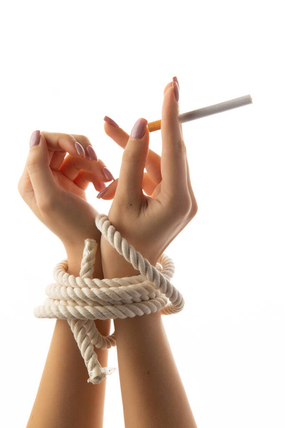 A megkötözött női kezek egy cigarettát tartanak elszigetelve fehér alapon.. - Fotó, kép