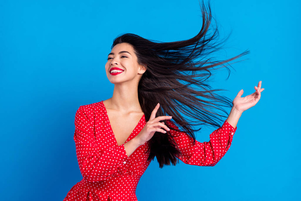 Photo portrait of smiling woman dancing in red dress with flying hair isolated on vivid blue color background - Foto, Bild