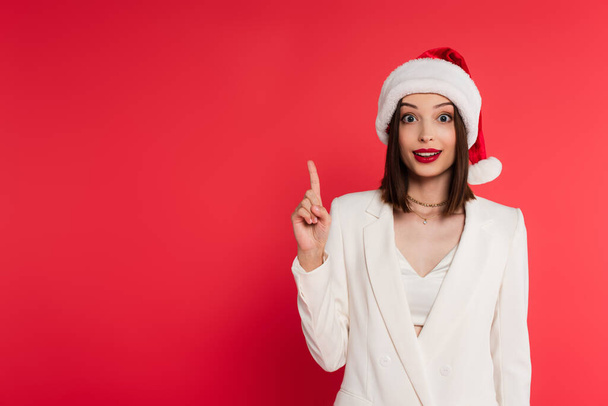 Excited woman in santa hat having idea isolated on red  - Foto, Imagen