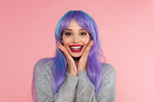 Excited woman with dyed hair and warm sweater looking at camera isolated on pink  - Foto, Imagen