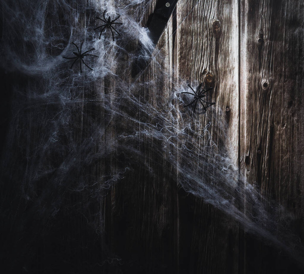 Spider web on wooden background with a knife. Halloween banner. Copy space. Selective focus. - Photo, Image