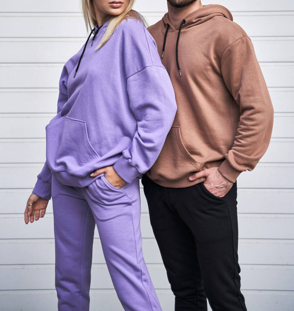 Der junge bärtige Mann und das blonde Mädchen stehen in schlichtem Kapuzenpulli zum Logodruck. Kleiderattrappe für Kapuzenpullover. Streetwear für Jugendliche im Herbst - Foto, Bild