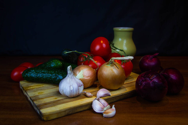 tomatoes, cucumbers and garlic on wooden longing. dark background - Foto, Imagem