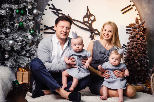 A happy big family with twin children in the New Year's interior of the house against the background of a large clock. - Foto, imagen