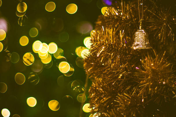 Christmas golden bell decoration on yellow background. Colorful blur bokeh background. Christmas background - Photo, Image