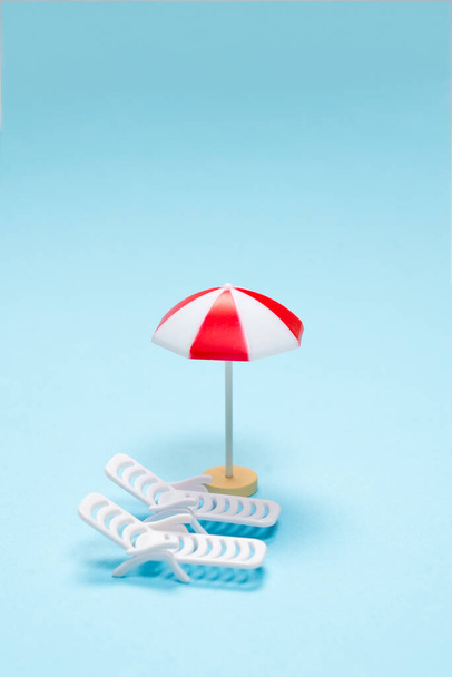 Travel concept. Sun lounger, red umbrella on a blue background. Copy space.  - Foto, Imagem
