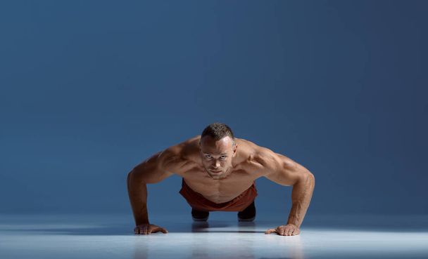 Athlète masculin faisant de l'exercice abdominal, séance d'entraînement en studio - Photo, image
