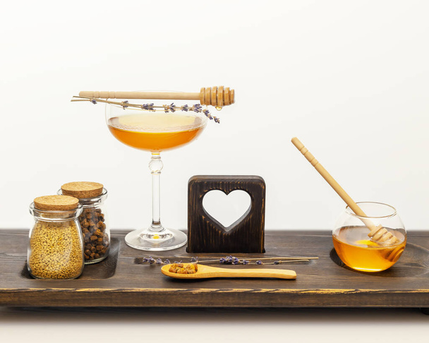 Natural, healthcare composition with bee products and honey in glass jars with honey dipper and lavender flowers on a wooden board on white table. Immune boosting food. Bee products are folk medicine - Fotoğraf, Görsel