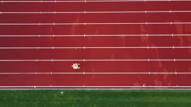 Sportovec běžící kousek od stadionu. Sportovní žena běží na červených běžeckých pásech - Záběry, video