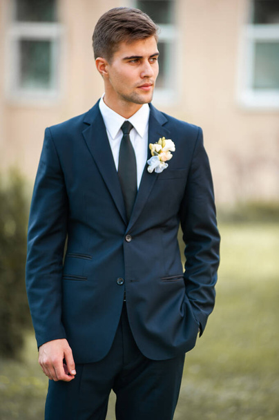 handsome groom in suit and tie posing outdoors - Foto, afbeelding