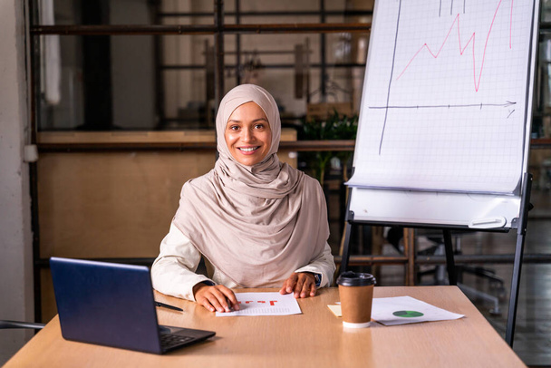 Beautiful middle-eastern businesswoman wearing hijab working in her office - 写真・画像