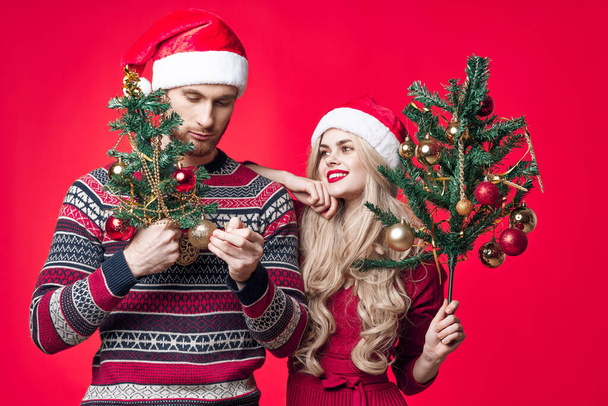 元気な若いカップルで新年の服の装飾おもちゃ赤の背景 - 写真・画像
